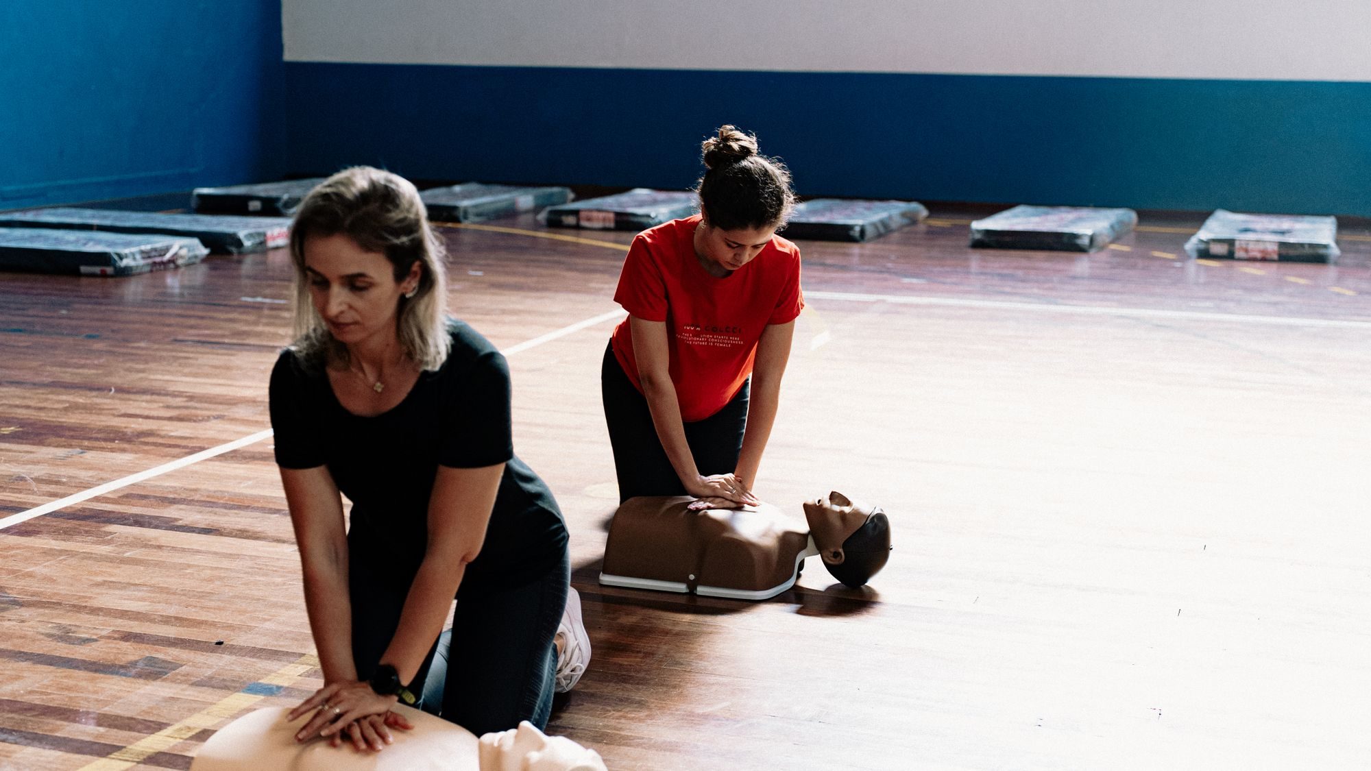 Two learners practising CPR on manikins in a training session