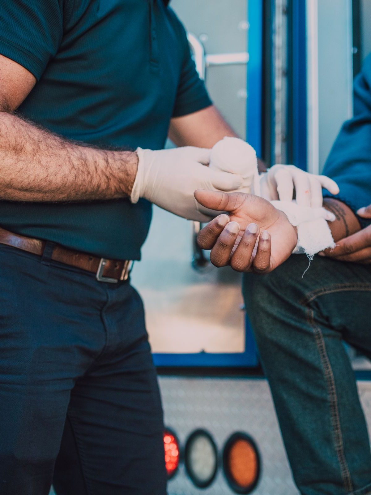 A responder giving first aid to an injured man beside an ambulance