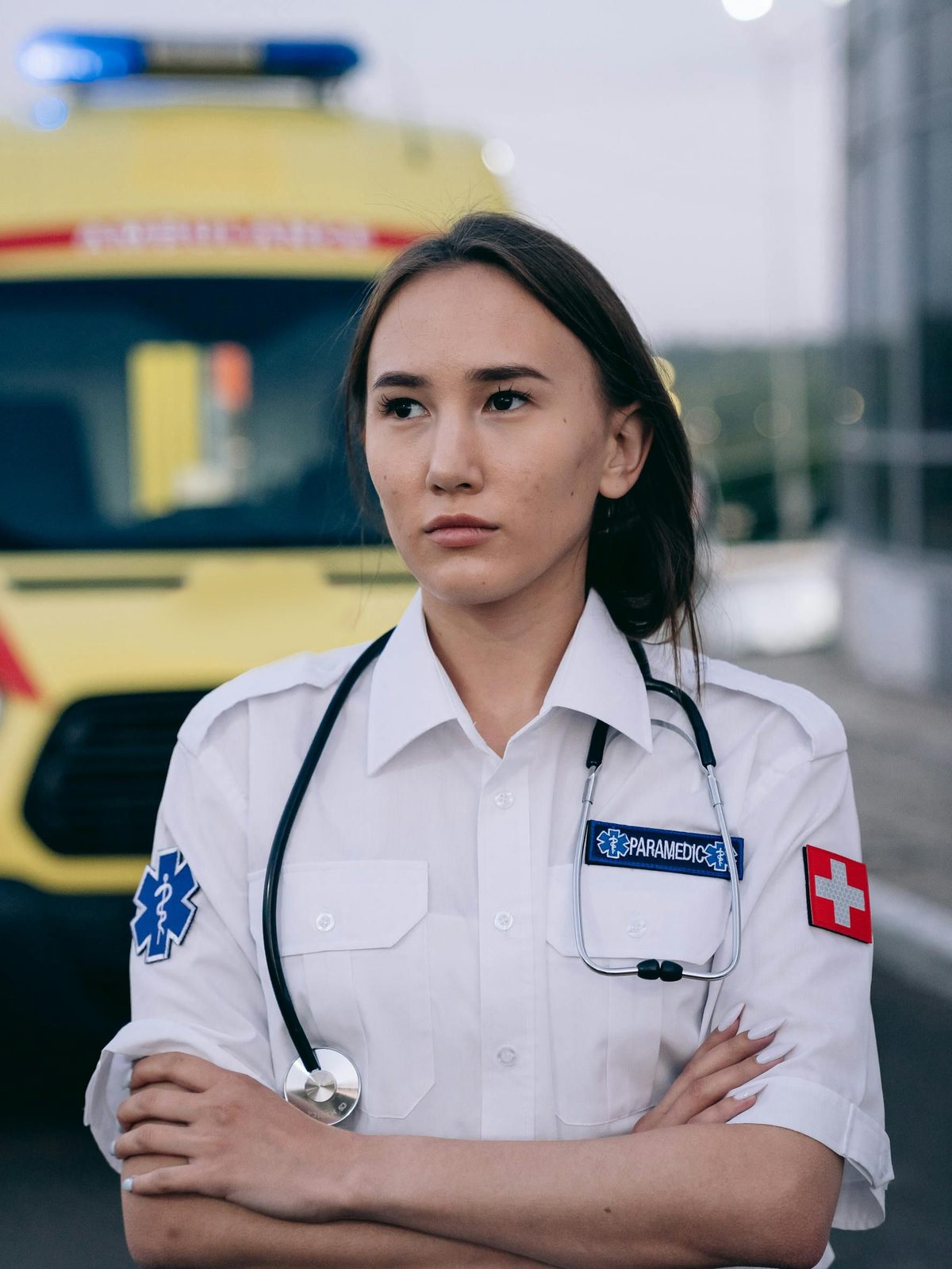 A paramedic with a stethoscope standing in front of an ambulance
